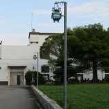 Quello che riusciamo a vedere attraverso il cancello � un edificio che si sviluppa su due piani, a base rettangolare e bianco, arricchito solo con fasce monocrome marroni
